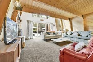 a living room with a couch and a tv at Quail's Call Big Bear~ Walk to Lake & Ski Resort in Big Bear Lake