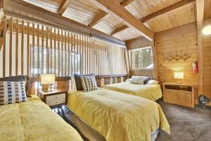 two beds in a room with wooden walls at Quail's Call Big Bear~ Walk to Lake & Ski Resort in Big Bear Lake
