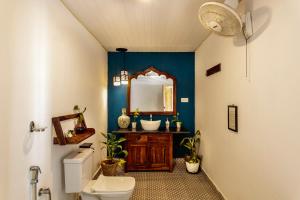 a bathroom with a sink and a mirror and a toilet at Agonda Cottages in Agonda