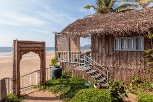 a building on the beach with an arch and stairs at Agonda Cottages in Agonda