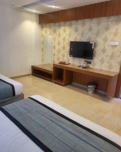 a hotel room with a bed and a flat screen tv at Hotel Sai D-lax in Shirdi