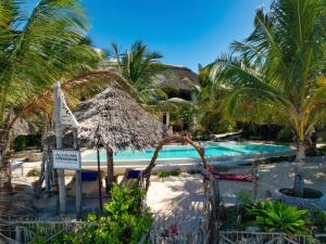 a resort with a swimming pool and palm trees at Villa Juliana in Jambiani