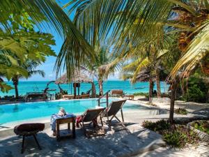 a person sitting at a table next to a swimming pool at Villa Juliana in Jambiani