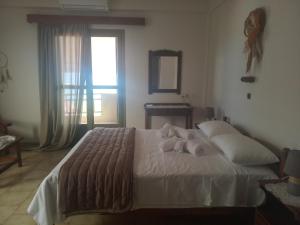 a bedroom with a white bed with a window at Buganvilla Sea View apts in Agia Pelagia