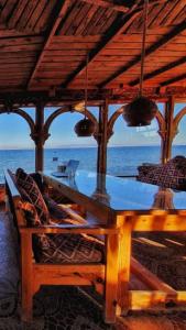 a wooden table and chairs under a roof with the ocean at Mirage Village in Dahab