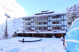a building with snow on the ground in front of it at Yashshree Lachung in Lachung