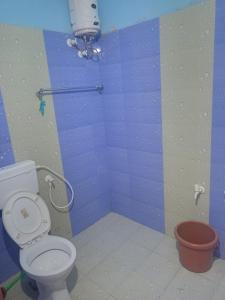 a bathroom with a toilet and a blue wall at Ruvi Beach front Ac rooms in Gokarna