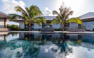 a swimming pool in front of a house with palm trees at Luxury Vacation Villa 20 in Pointe Milou