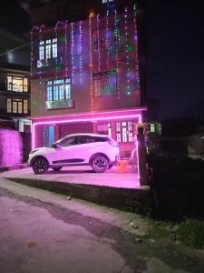 a white car parked in front of a house with christmas lights at BLUE DUKE HOMESTAY in Ravangla