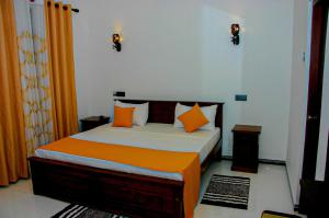 een slaapkamer met een bed met oranje en witte kussens bij Sigiri Heaven Villa in Sigiriya