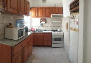 cocina con armarios de madera y horno de fogón blanco en Alojamiento Boj en Deán Funes