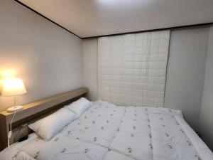a bedroom with a white bed with a lamp at Yeongdeungpo Windsor in Seoul