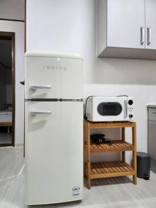 La cocina está equipada con nevera blanca y microondas. en Yeongdeungpo Windsor en Seúl