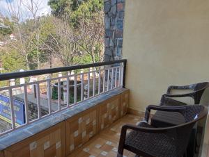 two chairs sitting on a balcony with a view at Atithi Homestay & Bhojnalya, Chail in Chail