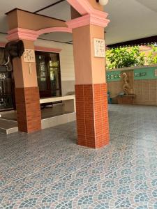 een lobby met zuilen en een tegelvloer in een gebouw bij บ้านมณียา in Noen Kra Prauk