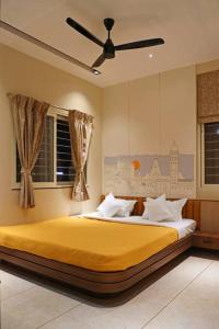1 dormitorio con 1 cama amarilla y ventilador de techo en Sumadhu Homes -Family Homestay en Kolhapur