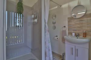 ein Bad mit einer Dusche, einem Waschbecken und einem Spiegel in der Unterkunft Sleep Haven Self-Catering Accommodation - Nelspruit in Nelspruit