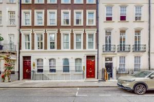 ein Auto, das vor einem Gebäude mit roten Türen parkt in der Unterkunft Park Lane Apartments Mayfair Collection in London