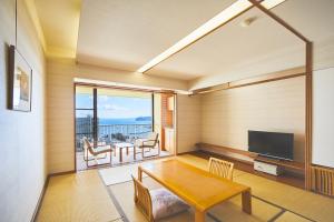 un soggiorno con tavolo e TV di Shiki Resort Atami Boyokan ad Atami