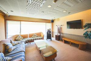 uma sala de estar com sofás e uma televisão de ecrã plano em Shiki Resort Atami Boyokan em Atami