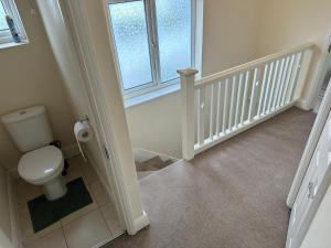 a bathroom with a toilet and a staircase with a window at House Dollis Hill in London