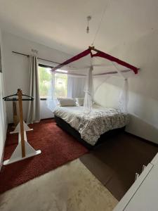 ein Schlafzimmer mit einem Himmelbett und einem Fenster in der Unterkunft Golden Bean Grove in Lusaka