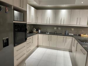 a kitchen with white cabinets and black appliances at SOMS Langstrand Self Catering in Langstrand