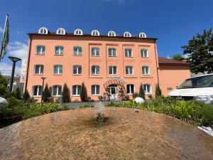 ein großes orangefarbenes Gebäude mit einem Brunnen davor in der Unterkunft Hotel Am Mühlenteich in Schwelm