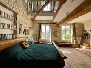 um quarto com uma grande cama verde e estantes de livros em The Old Winery, Loire em Le Puy-Notre-Dame