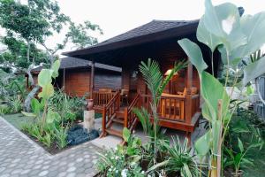 a wooden cabin with a porch in a garden at The Kori Sire in Tanjung