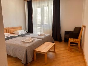 une chambre d'hôtel avec deux lits et une chaise dans l'établissement Beko’s garden Inn, à Mestia