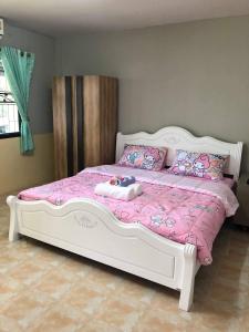 a bedroom with a white bed with pink sheets and pillows at Pani House ( Hatyai 2 ) in Hat Yai