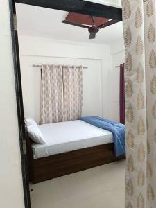 a small bed in a room with a curtain at 2BHK AC Service Apartment 101 Manjari in Pune
