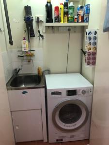 una pequeña cocina con lavadora y fregadero en phoenixonkingbnb en Buderim