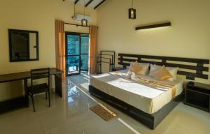 a bedroom with a bed and a table and a desk at Charlie Breeze in Ahangama