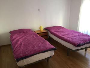 2 camas en una habitación con mantas moradas en Appartement Casa Rancurina, en Olivone