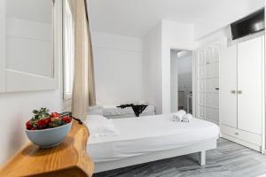 Dormitorio blanco con cama y plato de fruta en una mesa en Azur Mare Naxos, en Naxos Chora