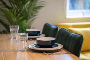 uma mesa de madeira com dois pratos e copos em Open Mind Property - City Centre & Free Parking em Southampton