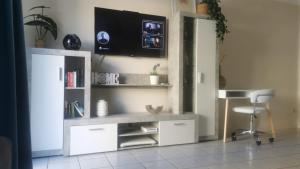 een woonkamer met een bureau en een tv aan de muur bij Rocas del Mar Apartment in Costa Del Silencio