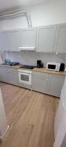 a kitchen with white cabinets and a counter with a microwave at Au pied du théâtre in Verviers