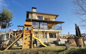 a house with a slide in front of it at Divna Guest House in Dospat