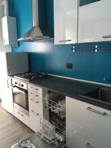 a kitchen with white cabinets and a blue wall at Pole Position Rho - Milano a portata di mano in Rho