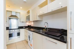 a white kitchen with a sink and a dishwasher at Apartment in the heart of Cardiff City Centre in Cardiff