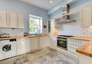 a kitchen with white cabinets and a washer and dryer at Meadow House in Blythburgh