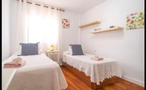 two beds in a room with white walls and wooden floors at Azahar - Vista Mar in Rincón de la Victoria