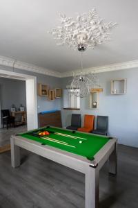 uma sala de estar com uma mesa de bilhar e um lustre em CHAMBRE D'HOTE em Granges-sur-Vologne