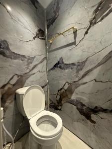 La salle de bains est pourvue de toilettes blanches et d'un mur en marbre. dans l'établissement Aladnan hotel, à Aqaba