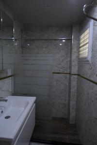uma casa de banho branca com um lavatório e um chuveiro em YILDIZHAN HOTEL em Pamukkale