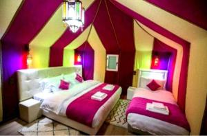 Merzouga Luxurious Camp في مرزوقة: غرفة نوم بسريرين بجدران ارجوانية وصفراء