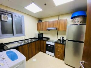 a kitchen with wooden cabinets and a stainless steel refrigerator at FT22 R3 Open beach ajman washroom is outside in Ajman 